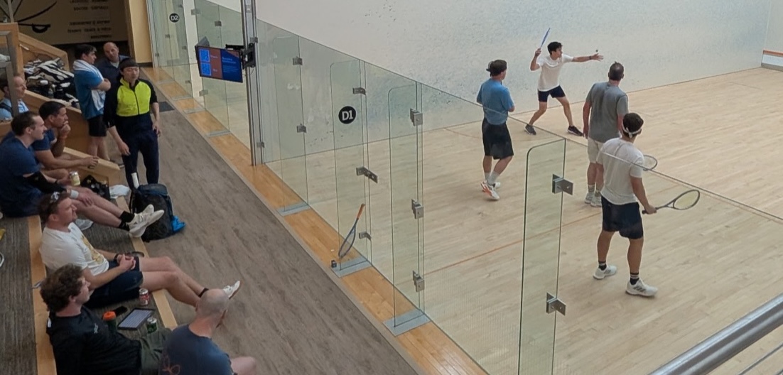 Players watching a River City Doubles match from courtside seating